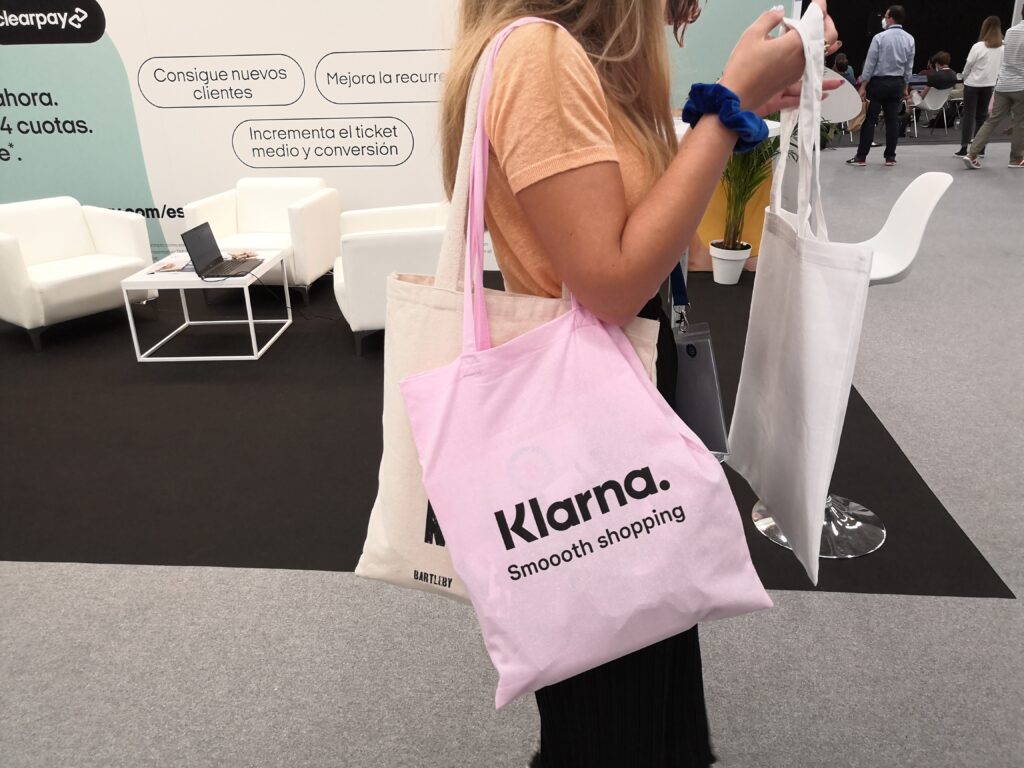 Femme portant plusieurs tote bag durant un salon
